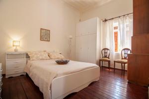 een witte slaapkamer met een bed en 2 stoelen bij Village House Volada in Karpathos