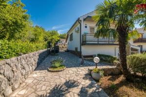 a stone walkway in front of a house with a palm tree at Apartment Moderna Soline in Dobrinj