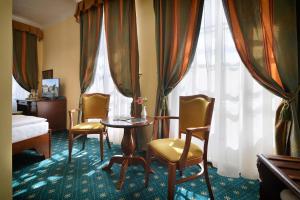 um quarto de hotel com uma mesa, cadeiras e cortinas em Hotel Certovka em Praga