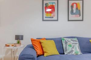 un sofá azul con almohadas coloridas en la sala de estar. en Bright 2 Bedroom House in Kennington en Londres