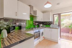 una cocina con armarios blancos y paredes verdes en Bright 2 Bedroom House in Kennington en Londres