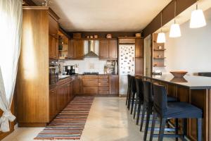 una cocina con armarios de madera y un bar con sillas en Villa Sofia, en Anavyssos