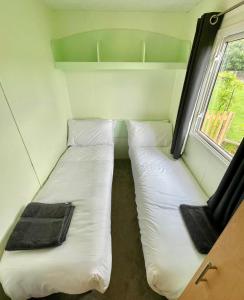 two beds in a small room with a window at Woodland Forge Lodge 