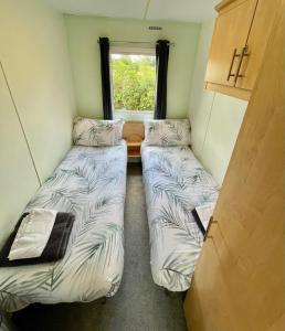 two beds in a small room with a window at Woodland Forge Lodge 