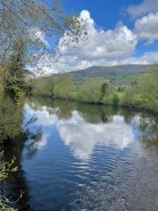 a river with a reflection of the sky in the water at Honeycott in Crickhowell