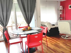 a dining room with a table and red chairs at Sol, mar y naturaleza in Pontevedra