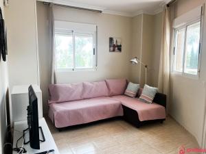 sala de estar con sofá rosa y TV en Modern apartment in front of the Mediterranean, en Oropesa del Mar