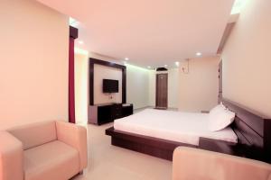 ein Schlafzimmer mit einem Bett, einem Stuhl und einem TV in der Unterkunft Hotel Orchid Blue in Ināni