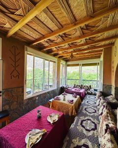 a dining room with two tables and a large window at La Petite Gorge, H&ocirc;tel & Restaurant Todra Gorge in Tinerhir