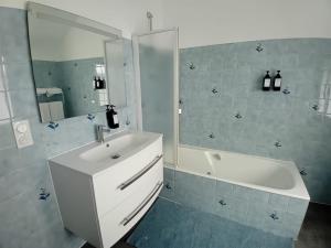 a bathroom with a sink and a tub and a mirror at VILLA CLARETTE in Carhaix-Plouguer