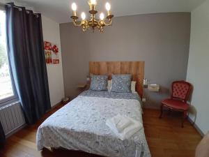 1 dormitorio con cama, lámpara de araña y silla en VILLA CLARETTE, en Carhaix-Plouguer