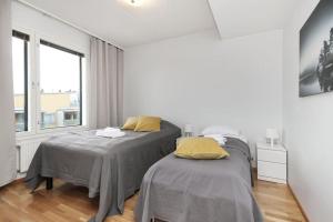 two beds in a white room with a window at Kotimaailma - Iso ja valoisa kaksio, Espoon Keskustassa in Espoo