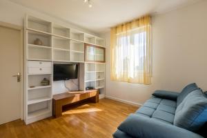 a living room with a blue couch and a television at Hana City Apartment in Split