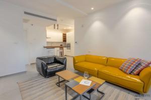 a living room with a yellow couch and a chair at Luxury Shenkin 2BR by Airsuite in Tel Aviv