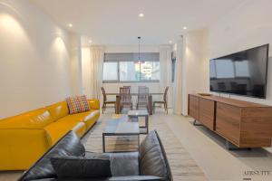 a living room with a yellow couch and a tv at Luxury Shenkin 2BR by Airsuite in Tel Aviv