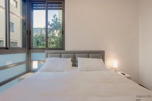 um quarto com uma grande cama branca e 2 janelas em Luxury Shenkin 2BR by Airsuite em Tel Aviv