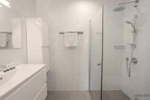 uma casa de banho branca com um chuveiro e um lavatório. em Luxury Shenkin 2BR by Airsuite em Tel Aviv