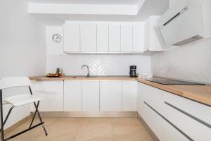 una cucina con armadi bianchi, lavandino e sedia di Casa Daura Playa de Arinaga 2023 Reformed a Arinaga