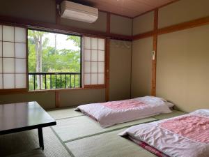 a room with two beds and a table and windows at Togawaso in Fujikawaguchiko