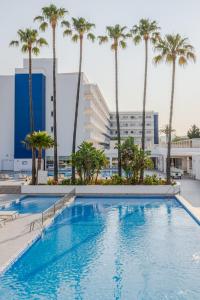 a swimming pool with palm trees and buildings at Globales Pionero in Santa Ponsa