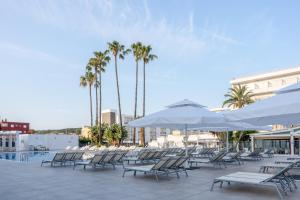 eine Terrasse mit Stühlen, Sonnenschirmen und Palmen in der Unterkunft Globales Santa Ponsa Park in Santa Ponsa