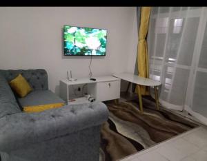 een woonkamer met een bank, een tafel en een tv bij Beta Two Apartment in Nairobi