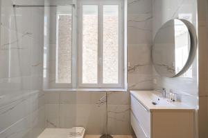 ein weißes Badezimmer mit einem Waschbecken und einem Spiegel in der Unterkunft Nice decorated apartment - near Croisette - 1BR4p in Cannes