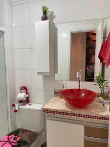 uma casa de banho com um lavatório vermelho e um espelho. em Apartamento Mari 4 em São Carlos
