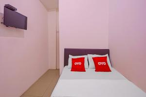 a bedroom with two red pillows on a bed at Super OYO 92664 Cemara Koja Residence Syariah in Jakarta
