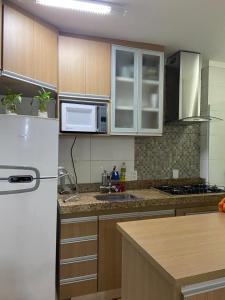 uma cozinha com armários de madeira e um frigorífico branco em Apartamento Mari 4 em São Carlos