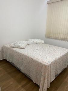 uma cama num quarto branco com uma janela em Apartamento Mari 4 em São Carlos