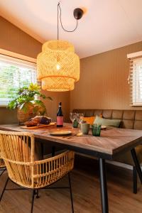 jadalnia z drewnianym stołem i żyrandolem w obiekcie Luxe hippe Lodge in de bossen van Oisterwijk w mieście Oisterwijk