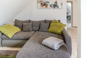 - un canapé gris avec des oreillers jaunes dans le salon dans l'établissement Apartment#1, à Kerpen