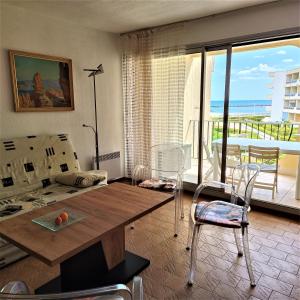 een woonkamer met een tafel en uitzicht op de oceaan bij Front de plage in Palavas-les-Flots