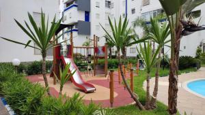 a playground in a resort with a slide at Appartement cosy à BOUZNIKA in Bouznika