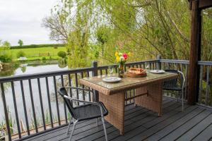 una mesa de picnic en una terraza con vistas al agua en Lily pad Lodge en Rous Lench