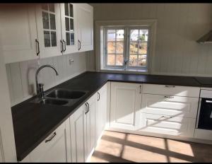 a kitchen with white cabinets and a sink and a window at Waterfront Cottage (Fishing Opportunities!) in Ålesund