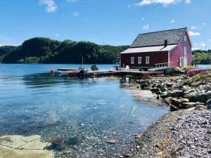 uma casa vermelha na margem de um lago em Waterfront Cottage (Fishing Opportunities!) em Ålesund