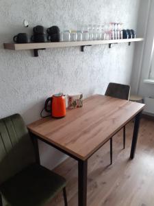 un hervidor de té naranja sentado en una mesa de madera con 2 sillas en Our Little World en Liepāja