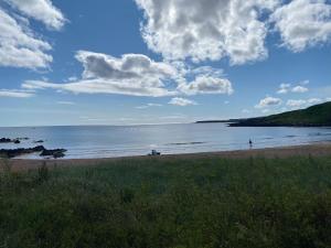 a beach with people on the sand and the water at Sandy Top in Saint Abbs