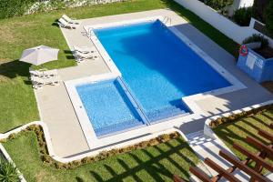 een uitzicht op een zwembad met stoelen en een parasol bij LEGACY SUITES & APARTMENTS ALBUFEIRA AL in Albufeira