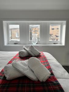 een bed met twee handdoeken erop met drie ramen bij Very Central, Charlotte Square, near the Castle in Edinburgh +9 foto's