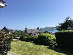 a garden with hedges and a bench in front of a house at Rhuside in Campbeltown