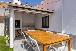 einen Holztisch und Stühle auf der Terrasse eines Hauses in der Unterkunft Lovely Beach House in Aroeira by LovelyStay in Aroeira