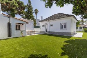 ein kleines weißes Haus mit einem grünen Rasen in der Unterkunft Lovely Beach House in Aroeira by LovelyStay in Aroeira