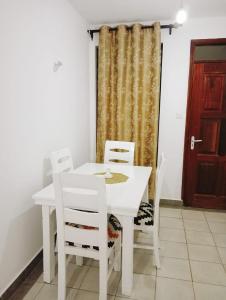 una mesa blanca y sillas en una habitación con puerta en Three Bedroom Thika Road, en Nairobi