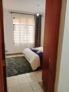 um quarto com uma cama, uma janela e uma porta em Three Bedroom Thika Road em Nairobi