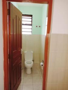 een badkamer met een toilet en een open deur bij Three Bedroom Thika Road in Nairobi