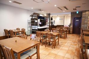 uma sala de jantar com mesas e cadeiras de madeira em Nagano Daiichi Hotel em Nagano