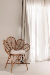 a rattan chair sitting in front of a window at White Suites in Ermoupoli